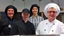 Eeva Nieminen, Ville Mikkola, Kaarina Lindroos ja Sirpa Salminen hymyilevät työpaikallaan Nurmijärven yhteiskoulun keittiössä.