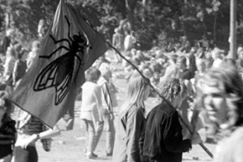 Kuva: Nuori pariskunta kantaa krpsen kuvalla varustettua lippua Ruisrockissa. (1970) YLE kuvanauha.