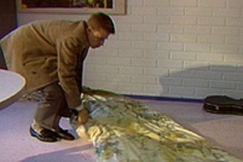 Kuva: Sam Inkinen levittää patjaa työhuoneen lattialle. (1989) YLE kuvanauha.
