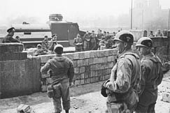 Kuva: Berliinin muuri. Yhdysvaltalaisia sotilaita seuraamassa kun DDR:n rajavartijat muuraavat umpeen  loikkareiden tekemää aukkoa. (1963) Pressfoto.