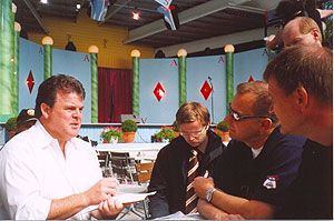 John Carney keskustelee ohjelman tuottajien Juha Vuorion ja Matti Grönbergin sekä ohjelman juontajan Matti Vannaksen kanssa.