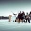 Bajo Cero-yhtyeen promokuva, jossa kuvattuna talvisessa maisemassa iloisia ihmisiä karvalakit päällä. Ja vieressä valkoinen poro. Aurinko paistaa.