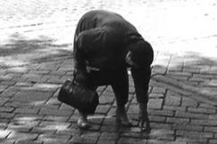 Kuva: Vanha nainen yritt irrottaa katuun liimattua seteli (1959). YLE kuvanauha.